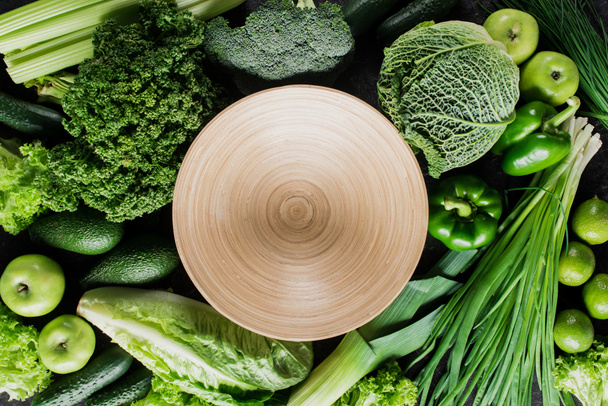 top view of cutting board between green vegetables, healthy eating concept - Zdjęcie, obraz