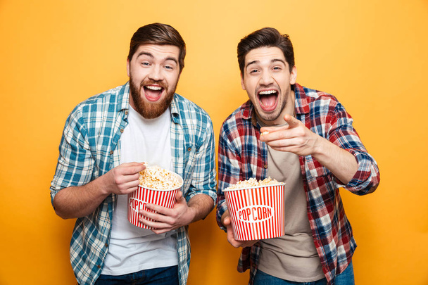 Портрет двох щасливих молодих чоловіків, які їдять попкорн
 - Фото, зображення