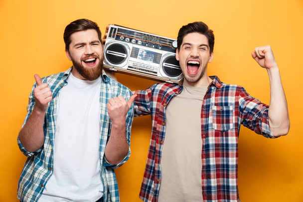 Two cheerful men in shirts listening music by record player - Φωτογραφία, εικόνα