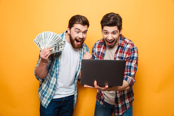 Portrait of a two joyful young men using laptop - Foto, imagen