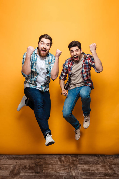 Full length portrait of a two excited young men celebrating - Foto, afbeelding