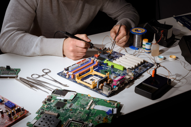 Engineer working with soldering equipment and motherboard - Photo, Image