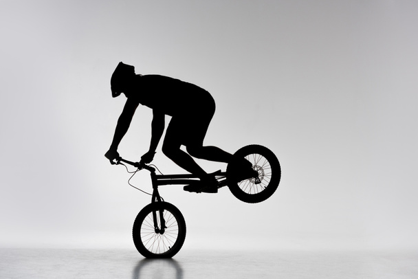 silhouette del ciclista di prova che esegue il cavalletto anteriore su bianco
 - Foto, immagini
