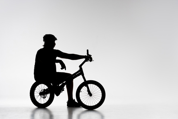 silhouette of trial biker relaxing on bicycle on white - Photo, Image