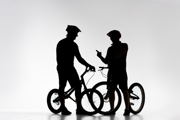 siluetas de ciclistas de trial con bicicletas charlando en blanco
 - Foto, imagen