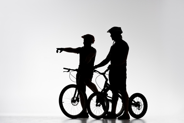 a próba kerékpárosok kerékpárokkal beszélgető-fehér sziluettek - Fotó, kép