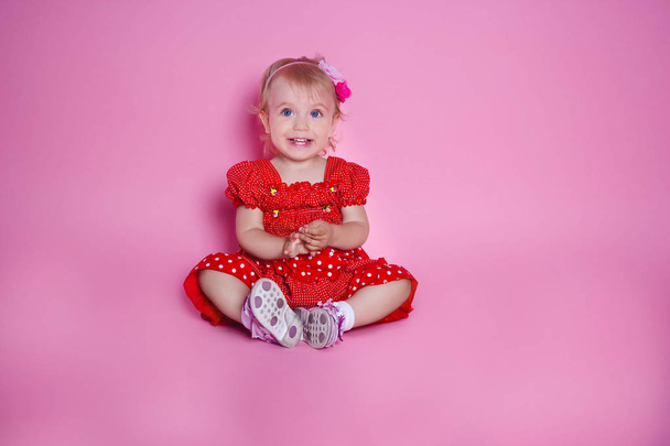  Niña está sentada sobre un fondo rosa
 - Foto, imagen