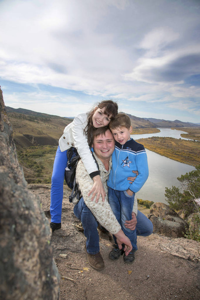 Una familia feliz en la montaña con vistas a la corriente bajo el
 - Foto, Imagen
