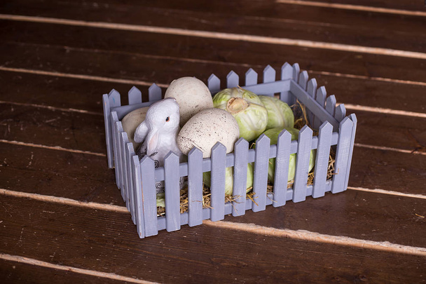 en el suelo de madera es una cesta con un conejo y col en el estudio. decoraciones de Pascua
 - Foto, Imagen
