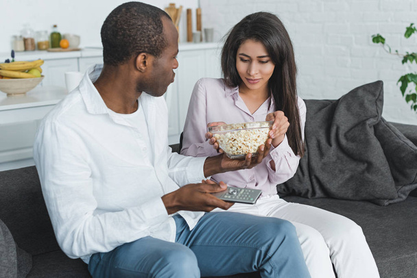 Αφρικανική αμερικανική φίλη και φίλο της τρώγοντας ποπ κορν και βλέποντας τηλεόραση στο σπίτι - Φωτογραφία, εικόνα