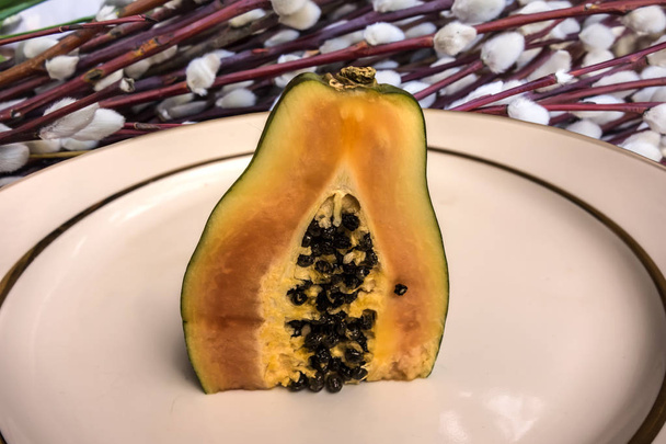 La mitad jugosa fresca de papaya en un plato blanco con un borde de oro
 - Foto, Imagen