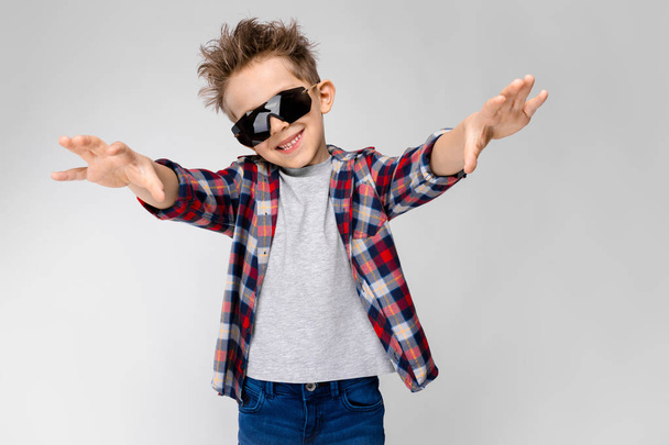 Szép kaukázusi óvodás fiú alkalmi ruhát és napszemüveg mutatja a különböző kifejezések fehér falon a stúdió. - Fotó, kép
