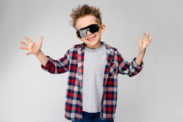 Szép kaukázusi óvodás fiú alkalmi ruhát és napszemüveg mutatja a különböző kifejezések fehér falon a stúdió. - Fotó, kép
