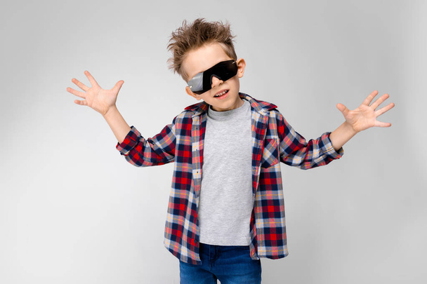 Nice caucasian preschooler boy in casual outfit and sunglasses showing different expressions on white wall in studio. - Photo, Image