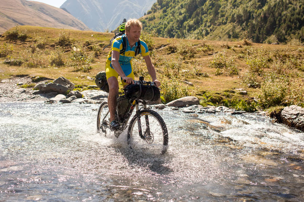 Ciclista de montaña está cruzando el río en las tierras altas de Tusheti
 - Foto, imagen