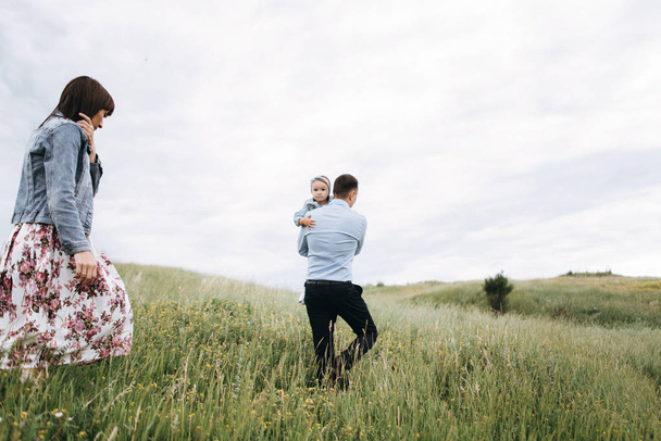 Visão traseira da família jovem passar o tempo juntos andando no campo
 - Foto, Imagem