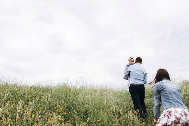 Rückansicht einer jungen Familie, die an einem grauen Tag gemeinsam spazieren geht - Foto, Bild