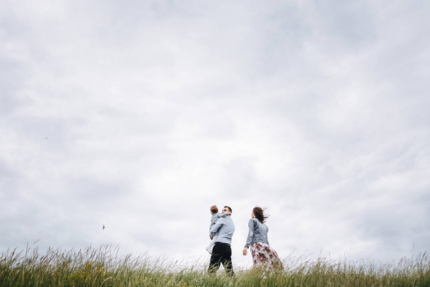 Vista inferiore della famiglia che cammina sul prato contro lo sfondo cielo nuvoloso
 - Foto, immagini
