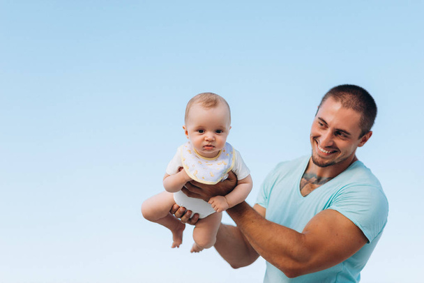 Onnellinen isä syleilee poikaansa sinitaivaalla
 - Valokuva, kuva