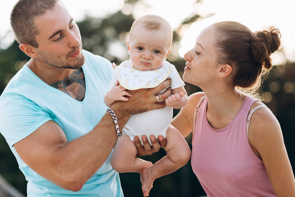 Happy family: mother, father and little baby boy having fun outside - Photo, Image
