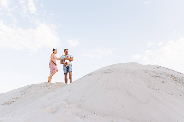 Happy family: mother, father and little baby boy outside on sand - Photo, Image