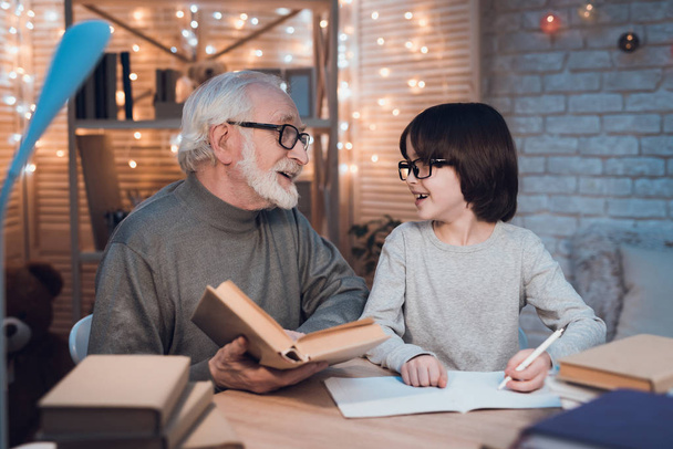 Grandfather helping grandson doing homework at table - Photo, image
