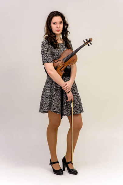 a girl in a dress is holding a violin - Foto, Imagem