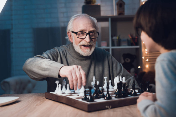 Avô e neto jogando xadrez juntos na mesa em casa
 - Foto, Imagem