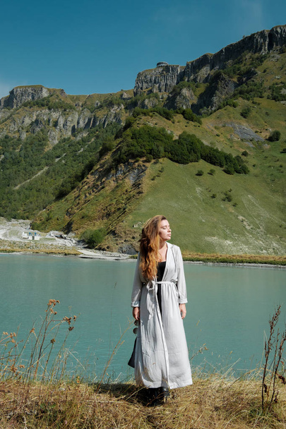 A girl stands by the lakes in the background of the mountains - Fotografie, Obrázek