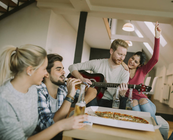 Onnellisia ystäviä soittamassa kitaraa ja kuuntelemassa musiikkia kotona - Valokuva, kuva