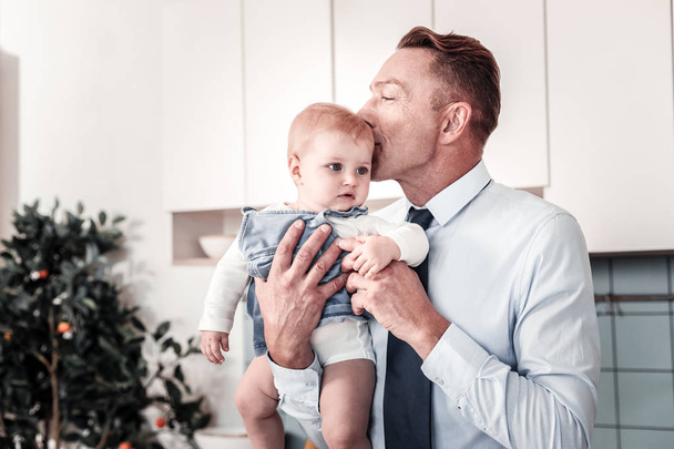 Positive delighted man kissing his baby boy - 写真・画像