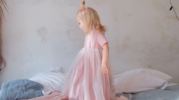 Little charming happy girl in beautiful pink dress on the bed. - Filmati, video