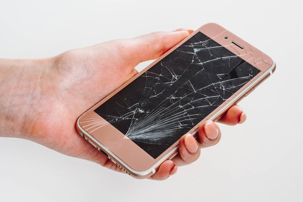 Broken glass screen of rose smartphone in hand, white background - Photo, Image