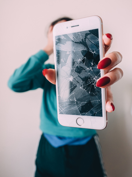 Teléfono inteligente pantalla de vidrio roto en la mano de la chica molesta, fondo blanco
 - Foto, Imagen
