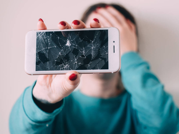 Kırık cam ekran smartphone üzgün kız, beyaz arka plan elinde - Fotoğraf, Görsel