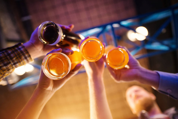 nuoret onnelliset miehet juhlivat ja paahtavat olutta pubissa
 - Valokuva, kuva