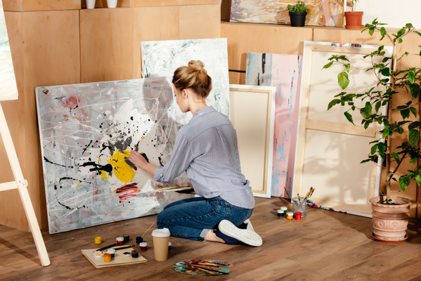 back view of attractive girl painting in art studio - 写真・画像