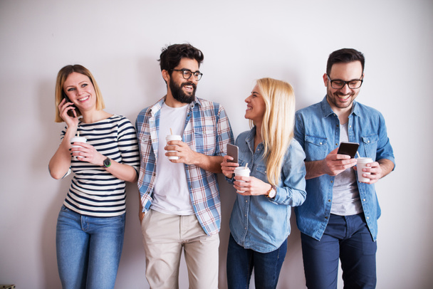 group of young happy coworkers having fun at break while drinking coffee and using gadgets - Photo, Image