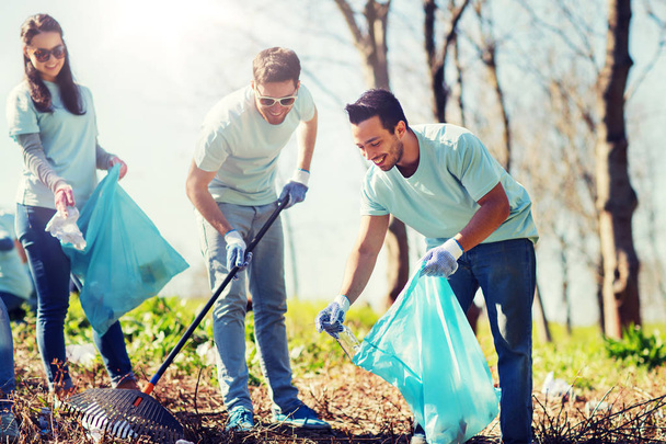 volunteers with garbage bags cleaning park area - 写真・画像