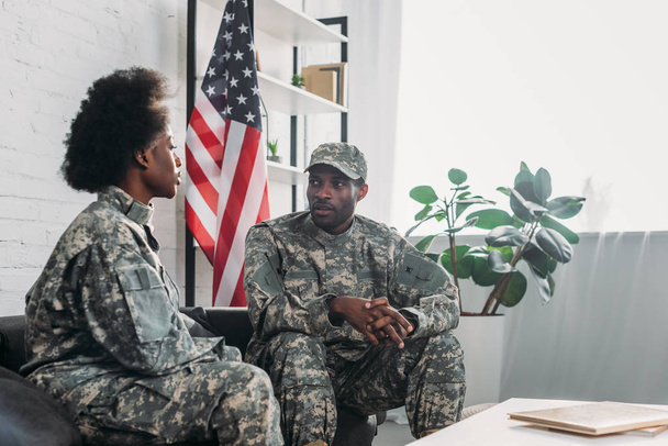 Woman and man in army uniform talking on sofa at home - Foto, Imagen