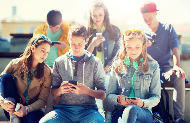 happy teenage friends with smartphones outdoors - Фото, зображення