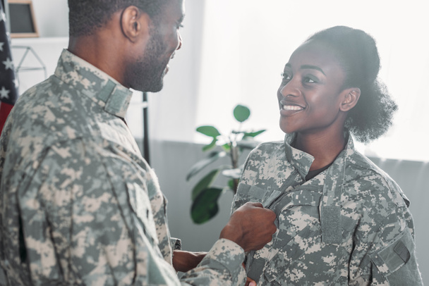 Soldado masculino ajudando mulher a se vestir com roupas de camuflagem
 - Foto, Imagem