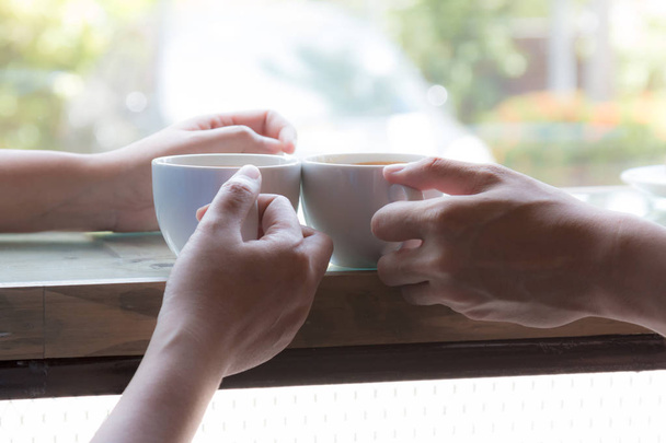 zwei Personen als Paar, die zusammen heißen Kaffee trinken, indem sie am Fenster des Cafés sitzen - Foto, Bild