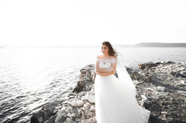 Romantic beautiful bride in white dress posing on the background sea - Photo, image