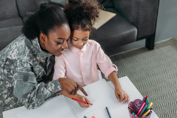African american woman in camouflage clothes and child drawing together - Foto, Bild