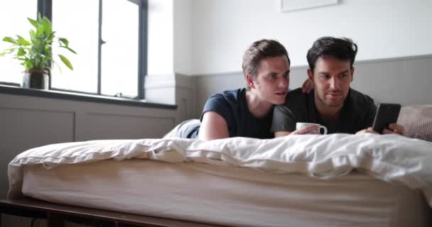Young male couple looking at smartphone together - Materiał filmowy, wideo