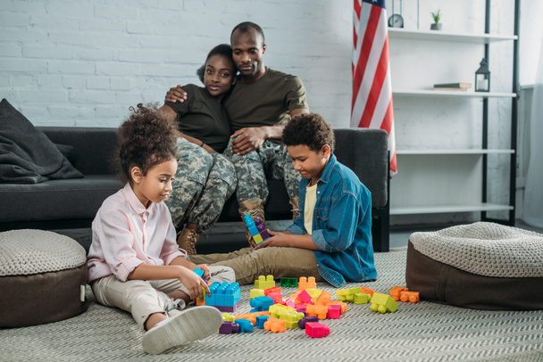 Parents in camouflage clothes looking at their children playing with cubes - Foto, immagini