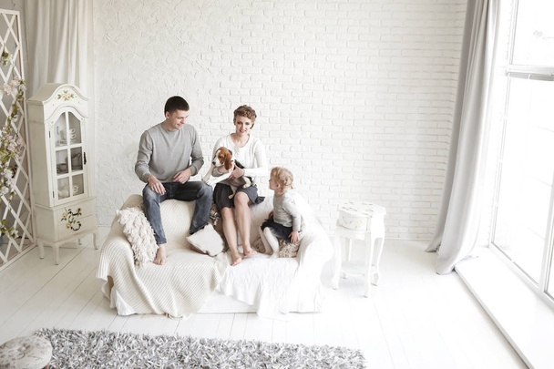 portrait of happy parents with their daughter and beloved pet with a living room - Фото, изображение