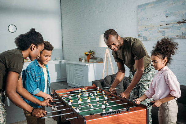 Família feliz de pais de soldados e crianças americanas africanas jogando futebol de mesa
 - Foto, Imagem