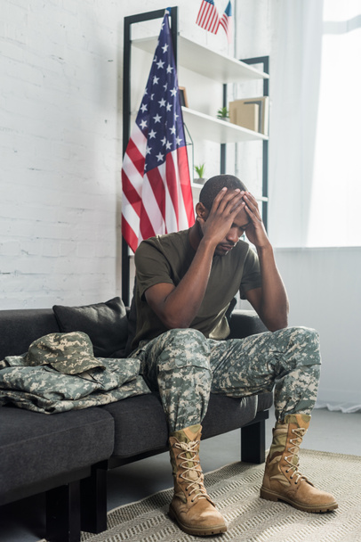 Upset army soldier sitting on sofa with camouflage clothes - Foto, afbeelding